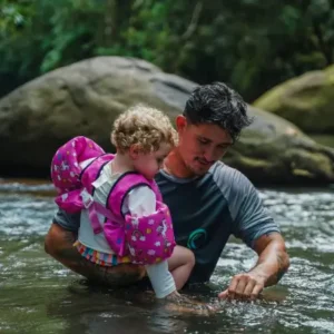 Tour guide assisting a toddler in a calm river during a Costa Rica family tour