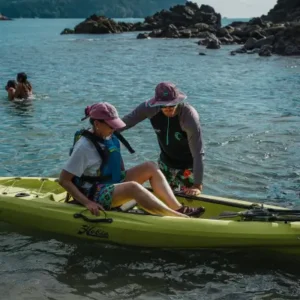 Tour guide assisting a family with a pedal kayak during a Costa Rica adventure.